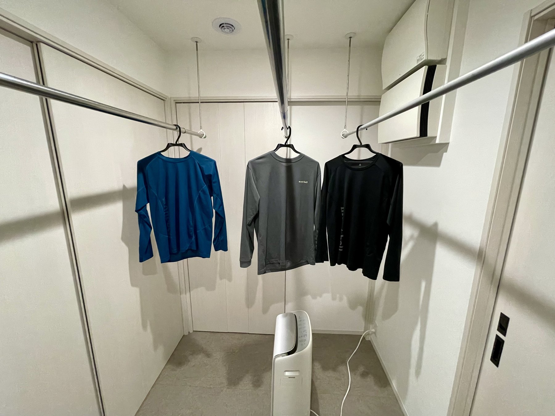 物干し竿に干した洗濯物と、その下で送風する衣類乾燥除湿機
